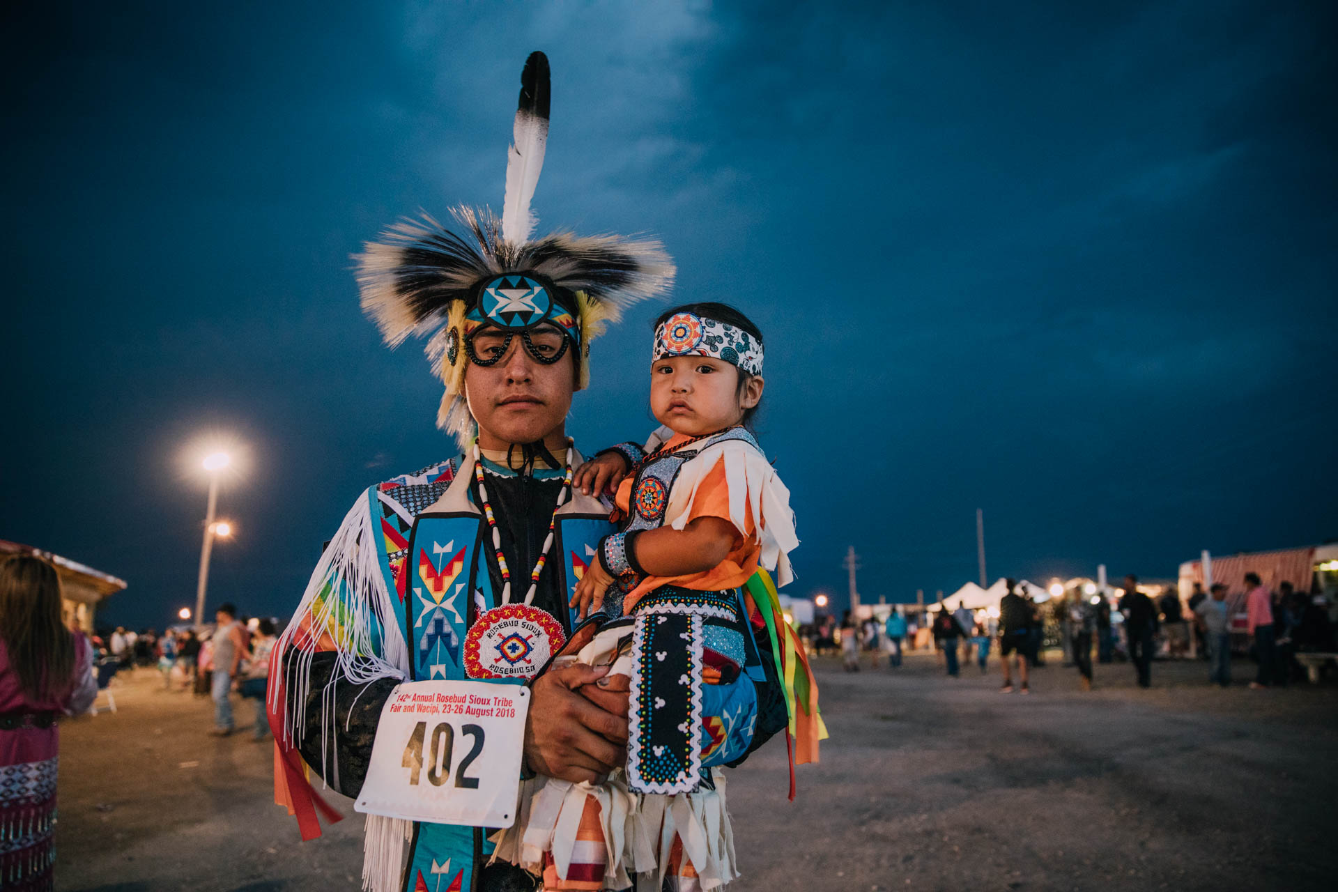 american-indian-fancy-dancer-with-feather-holding-child.JPG