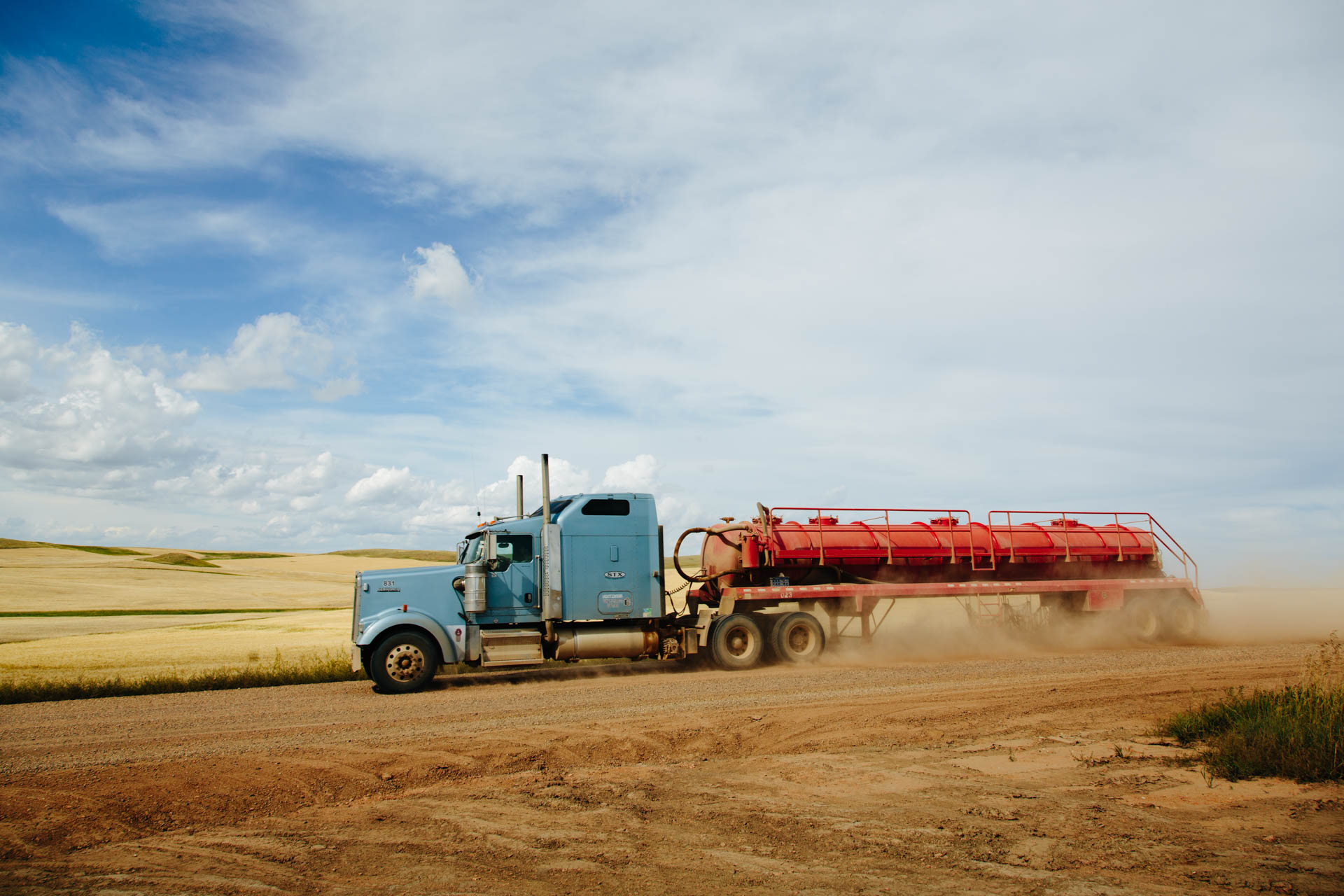 water-semi-kicks-up-dust-dirt-road-red-tank